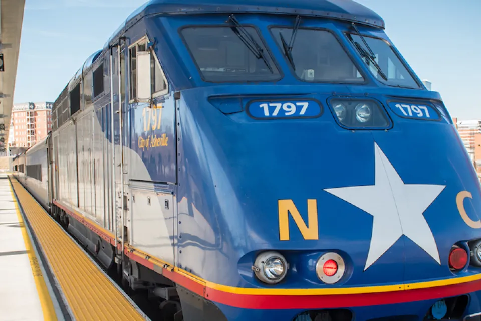 Blue train with white star and NC logo at platform in North Carolina.
